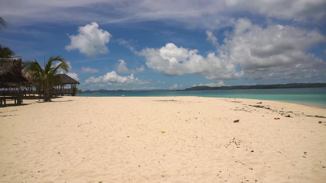 Beach with white sand with beach house on a tropical island Daco. Beautiful sky, sea, resort. Seascape: Ocean and beautiful beach paradise. Philippines. 4K video. Travel concept.