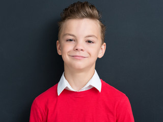 Close-up emotional portrait of caucasian teen boy. Funny teenager looking at camera on black background.