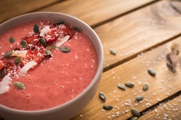 Strawberry, banana smoothie in the bowl. Wooden background..