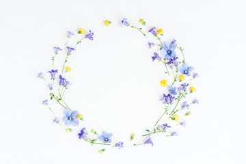 Wreath made of bell flowers, pansy flowers and yellow flowers on white background. Flat lay, top...