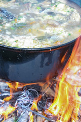 Fish soup boils in cauldron at the stake