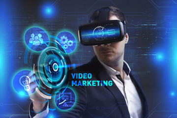 Business, Technology, Internet and network concept. Young businessman working in virtual reality glasses sees the inscription: Video marketing