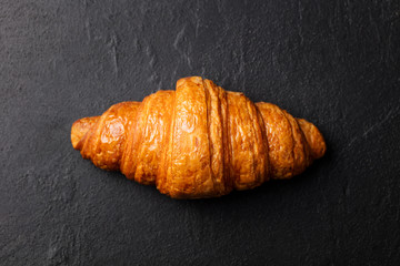 Fresh croissant on a black slate background. Top view. Copy space
