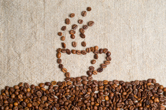 Spilled grains of fragrant coffee close-up. Photo frame, background. A cup of hot beverage, lined with coffee beans.