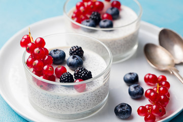 Chia seed pudding, cheesecake, custard dessert with fresh berries in a glass bowl on white plate