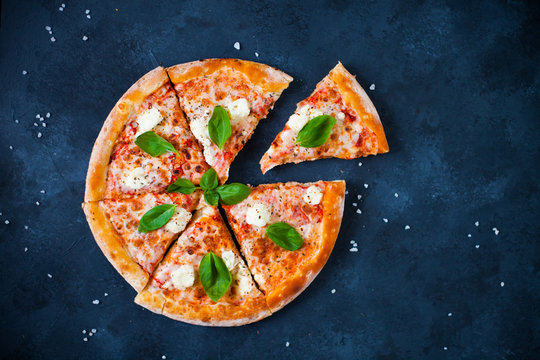 Homemade Pizza with tomato sauce,  olives,  fresh mozzarella, parmesan and basil on the dark background