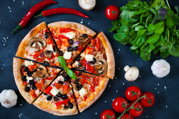 Homemade pizza with tomatoes, mozzarella and basil. Top view with copy space on dark concrete...