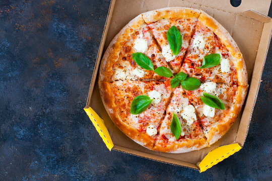 Pizza margarita with tomato sauce, fresh mozzarella, parmesan and basil on the dark  background