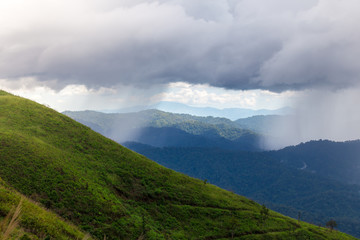Obraz premium green mountains under a dense clouds day.