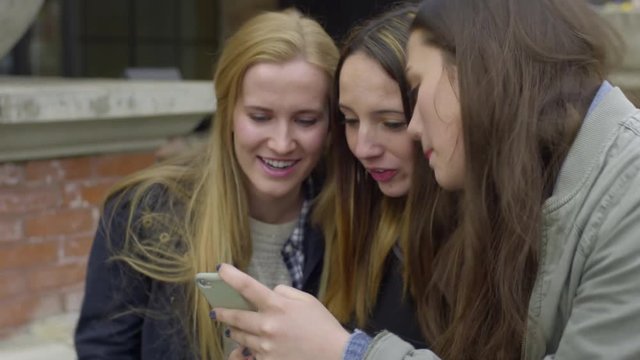 Closeup Of Group Of Friends Looking At A Smartphone, They Act Silly And Laugh