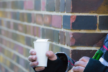 ein Bettler sitzt mit einer Flasche Wein an einer Strassenecke