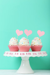 Tasty cupcakes on cake stand on green background