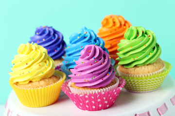 Tasty cupcakes on cake stand on green background