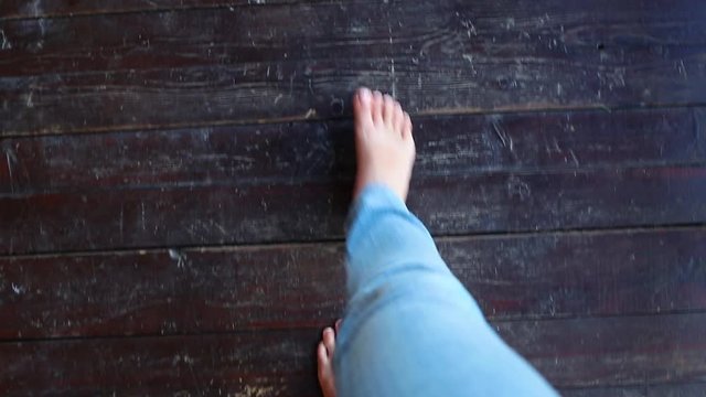 Point of view shot of beautiful white barefoot female legs. Adult woman walks slowly on brown wooden floor while enjoying holidays in countryside.  Top view real time full hd video footage.