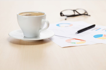 Office workplace with coffee cup and charts