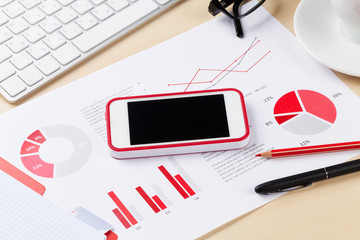 Office workplace with phone, charts and pc