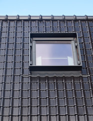 Black tiles of a new roof with an inserted window