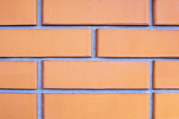 Brick wall close-up of orange bricks with smooth cement-sand seam