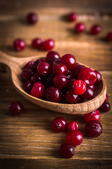 Cranberries in a spoon on a wooden background
