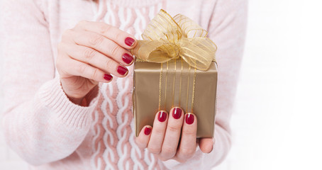 Woman holding golden Christmas present