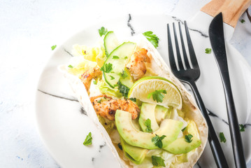 Healthy food snack. Tortillas taco with grilled chicken, avocado, fresh salsa, lettuce, lime. With yogurt & parsley sauce. On light gray stone marble table, marble plate. Copy space