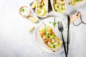 Healthy food snack. Tortillas taco with grilled chicken, avocado, fresh salsa, lettuce, lime. With yogurt & parsley sauce. On light gray stone marble table, marble plate. Copy space top view
