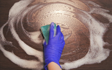 Closeup on woman's hands in blue protective rubber gloves cleaning kitchen and tiles. Instagram