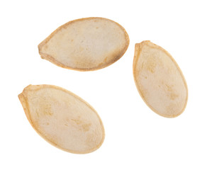 Three roasted and salted pumpkin seeds isolated on a white background.