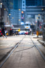 Fotobehang Hong Kong Street View / Streetcar tracks toward blurred urban traffic background with tram, car, unrecognizable people and city buildings at night (copy space) © 75tiks