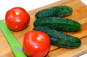 Fresh tomatoes and cucumbers on wooden Board for cutting