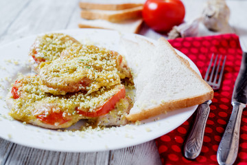 Baked chicken chops with tomato, cheese, dill, greens, spices, garlic and white bread toast on a light wooden background 