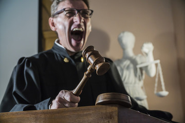 angry man a judge with a hammer in his hand in the court room shouts and cry