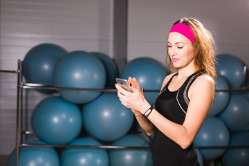 Fototapeta premium sport, fitness, technology and people concept - young woman with activity tracker and smartphone in gym