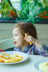 Little girl eating french fries in a restaurant.