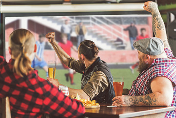 Joyful adult men drinking beer in bar