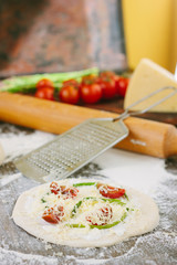 Cooking process of mini pizza with asparagus, tomatoes and cheese.
