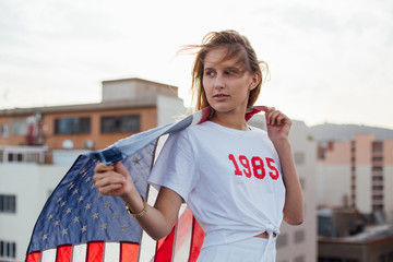 Trendy and modern young teenager poses on a professional photoshoot on a rooftop with an american symbol of independence
