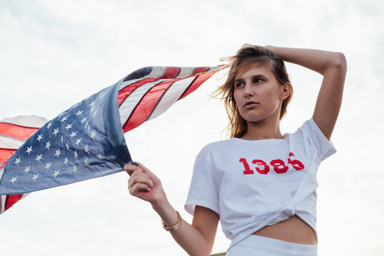 Silhouette Of Isolated Woman On The White Sky Holding An American Flag With Pride And Confidence As A Symbol Of Freedom