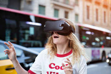  Funny cute girl tries to touch objects which are digitally projected into her VR headset