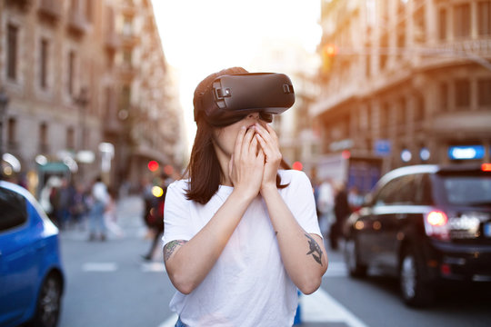 Attractive female hipster is surprised by what she sees inside the futuristic vr headset