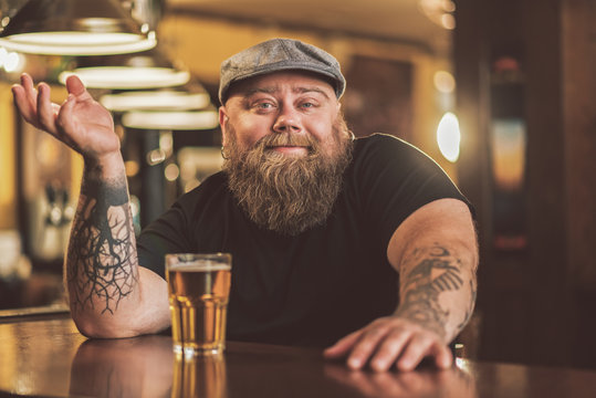 Smiling bearded male drinking beer in pub