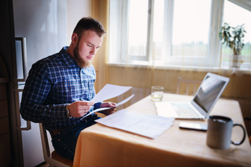 Handsome man doing some paperwork at home