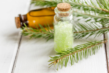 fir branches and spruce bath salt and aroma oil on white table background