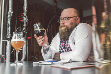 Confident guy working with concentration while standing in brewery
