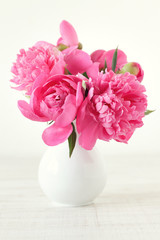 Pink peonies in vase on wood background