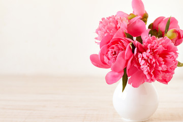 Pink peonies in vase on wood background