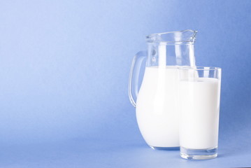Milk in a jar and a glass on a clear blue background