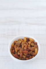 Bowl with raisins on bright wood background
