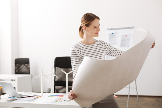 Cheerful female engineer holding a blueprint