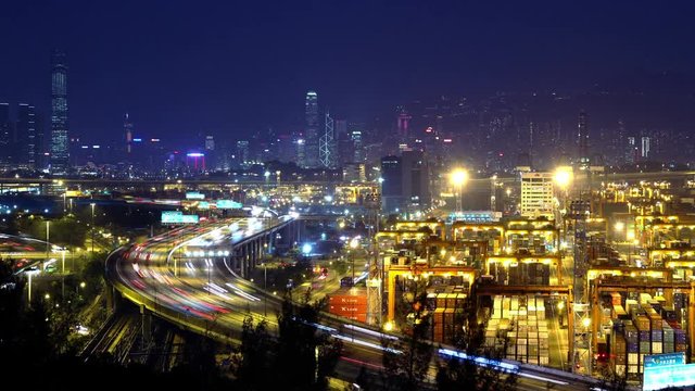 4K Busy City Timescape at Night. Hong Kong. Pan shot from busy traffic highway at the left to the cargo container terminal at the right. 